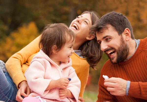 Happy family laughing and having fun together on picnic in autumn park.