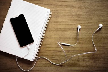 Ahşap arka planda akıllı telefon ve ofis aksesuarları