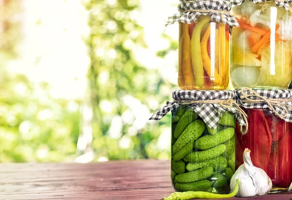 Pickled vegetables fermented process glass jars variety on table — Stock Photo, Image