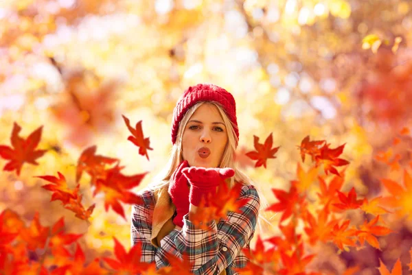 Autunno donna soffiando foglie di caduta Foto Stock