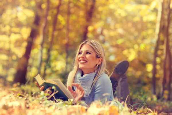 Portrait of a gorgeous blonde woman reading a book in the autumn — Stock Photo, Image