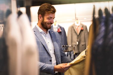 Erkek giyim mağazasında gülümseyen yakışıklı bir adam.