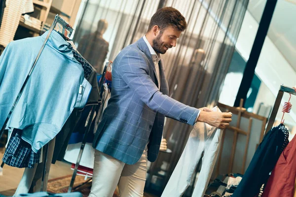 Homme à la mode dans un magasin de vêtements pour hommes choisissant des pantalons — Photo