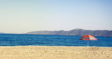 Sahilde renkli çizgili plaj şemsiyesi, tropikal yaz afişi.