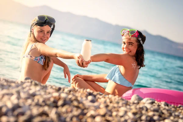 Dwie Uśmiechnięte Dziewczyny Maskach Nurkowania Trzymające Butelkę Kremu Opalania Plaży Zdjęcie Stockowe