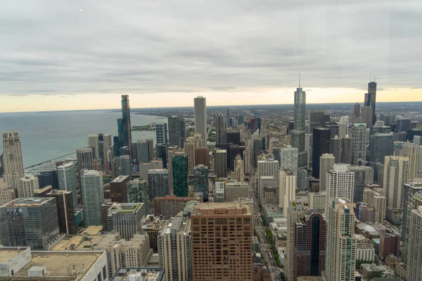 aerial view of chicago, showing some of the tallest buildings in the city. You can also see the lake and in the background you can see the sunset