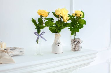 Nötr arka plan beyaz masada beyaz sürahi içinde Sarı Gül