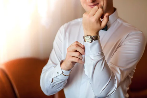 Kırpılmış bir çerçeve bir iş takım elbise, beyaz gömlek close-up bir adam. İşadamı kol düğmesi koyar, bir altın parmak yüzük parmağını, bir pahalı deri kemer takıyor.