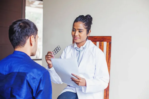 Junge indische Ärztin berät eine Patientin, während sie mich hält — Stockfoto