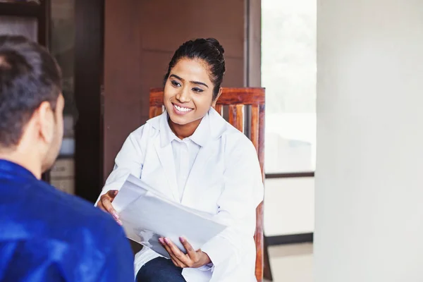 Young female Indian doctor consulting a patient while holding me