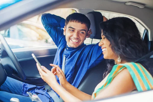 Beautiful indian couple in a car using mobile phone to plan thei — Stock Photo, Image