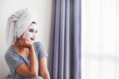Genç Asyalı kadın evde maske takıyor.