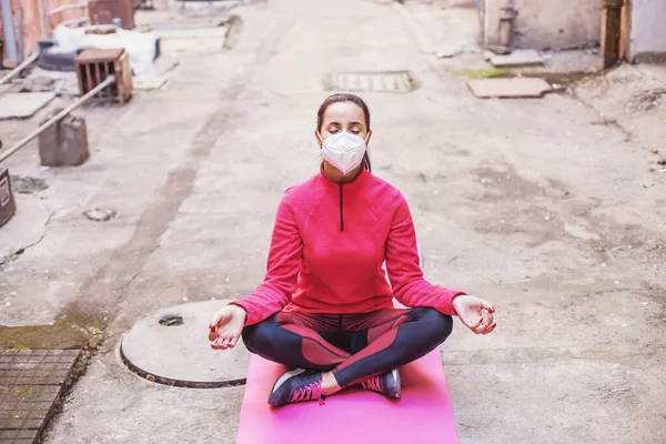 Woman wearing protection mask and meditating in polluted city