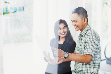 Asyalı ofis arkadaşları bir belgeyi tartışıyor