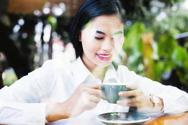 アジア系の若い女性がコーヒーを飲む 窓からの眺め — ストック写真