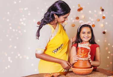 Güzel Hintli anne ve kız Navratri 'de Kalasha ile dua edip puja yapıyorlar, küçük kız kameraya bakıyor.