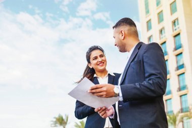 İki iş adamı ofis binasının dışındaki sözleşmeyi tartışıyor.