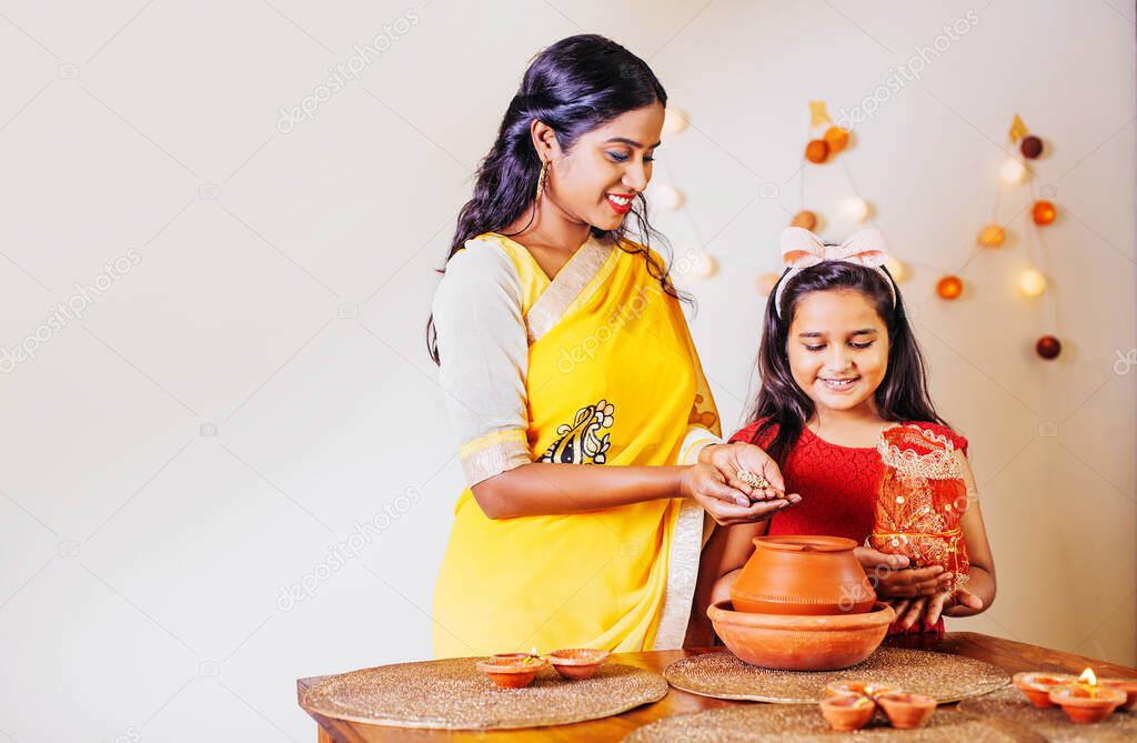 Beautiful Indian mother and daughter praying and doing puja with kalasha on Navratri days