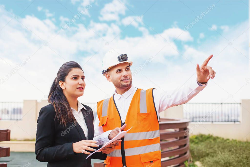 Indian architect/engineer showing building on construction site to a business woman