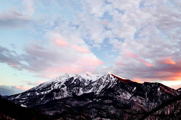 En grupp moln på himlen över ett snötäckt berg — Stockfoto