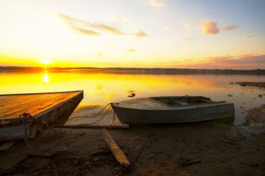 parlak ışıkta gün batımında sahilde tekne