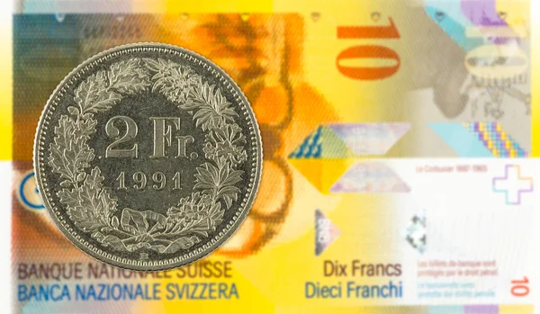 2 swiss franc coin against 10 swiss franc bank note