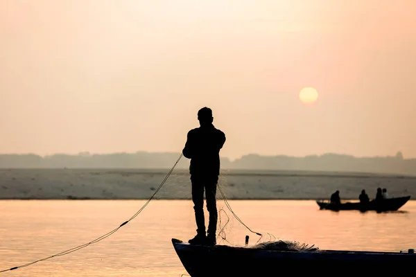 fisherman throws net in the sunrise on Ganges river, Varanasi, Uttar Pradesh, India