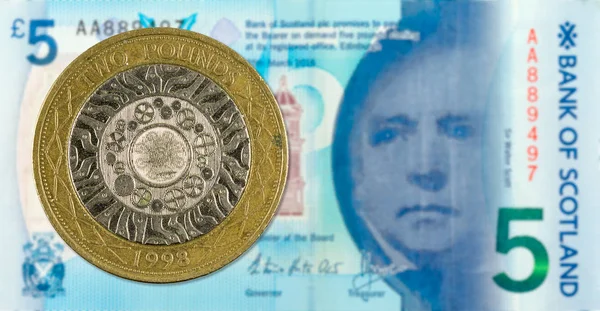 2 Pounds coin against 5 Pounds Sterling note issued by Bank of S