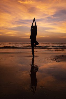 Gün batımında sahilde meditasyon bir genç adam silüeti