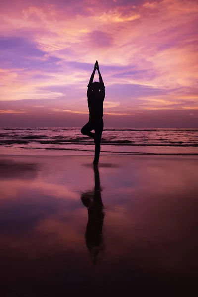 Gün batımında sahilde meditasyon bir genç adam silüeti