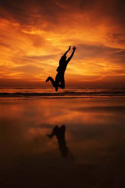 Bir adam silüeti kumsalda havada atlama