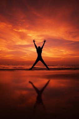 Bir adam silüeti kumsalda havada atlama