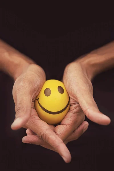 Hand squeeze yellow stress ball against black background