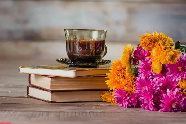 cup of coffee books and a bouquet of chrysanthemums
