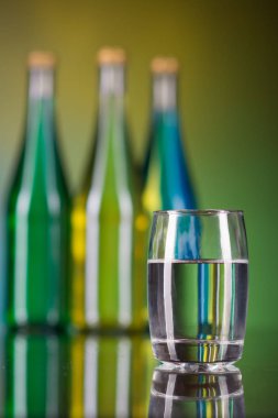 bir bardak su ve şişe renkli arka plan üzerinde