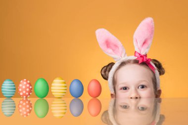 Boyalı yumurtaile masanın yanında bir tavşan kulakları ile kız 