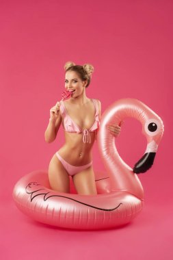 elinde bir lolipop ve şişme flamingo ile bir mayo güzel sarışın