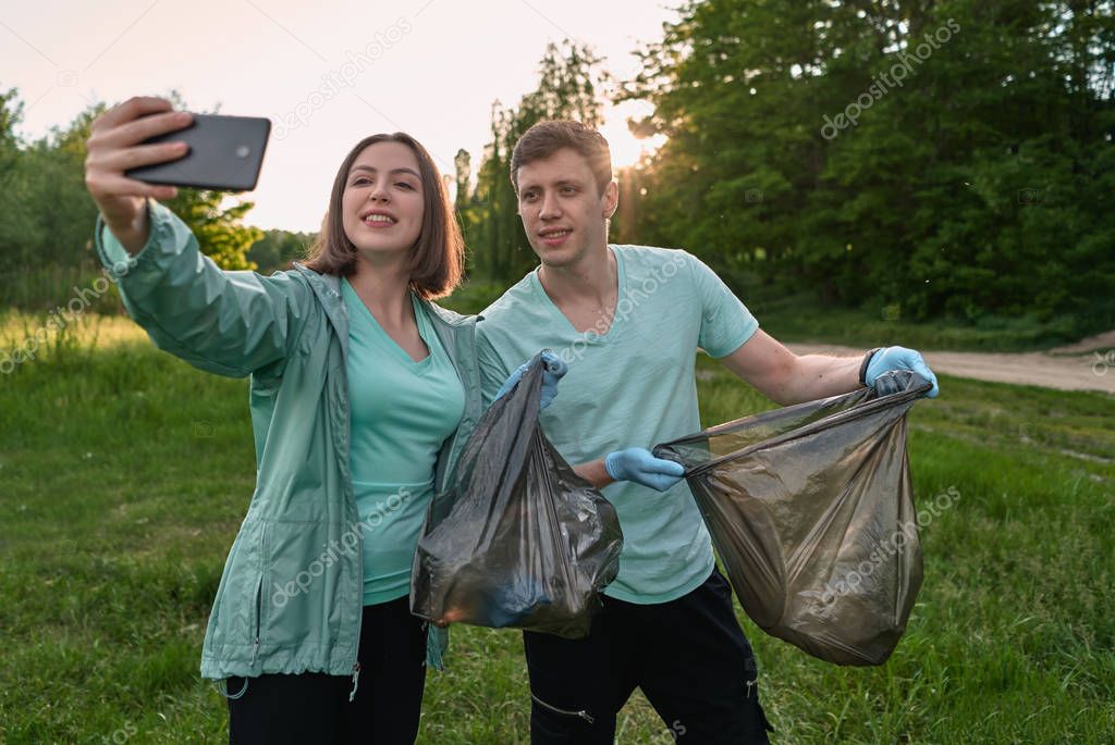 Plogging concept. Boy and girl picking up trash from the forest. They collecting the litter in garbage bag