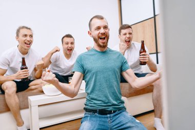 Cips patlamış mısır yerken ve soğuk bira içerken Tv izleyen arkadaşlar