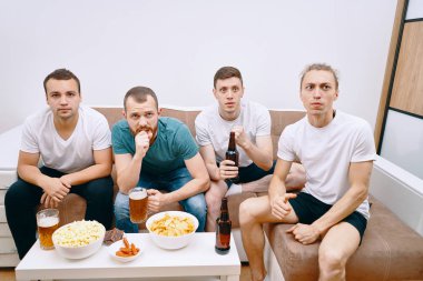 Cips patlamış mısır yerken ve soğuk bira içerken Tv izleyen arkadaşlar