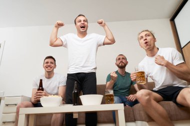 Cips patlamış mısır yerken ve soğuk bira içerken Tv izleyen arkadaşlar