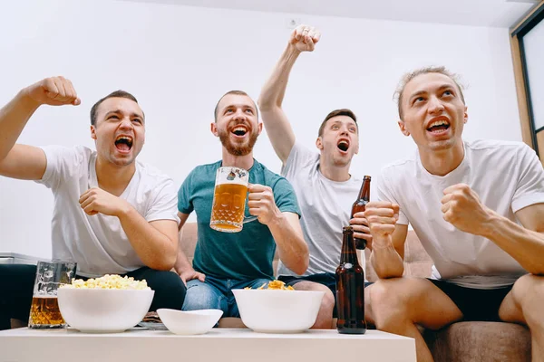 Friends watching Tv  while eating chips popcorn and drinking some cold beer