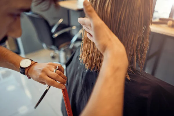 man hairdresser cuts hair of beautiful blonde woman