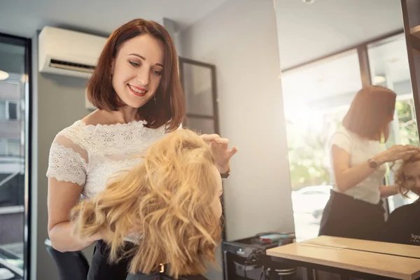female hairdresser styling a beautiful blonde