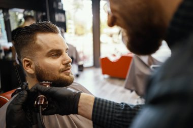 bir adam bir saç kesimi yapıyor ve sakal şekillendirme 