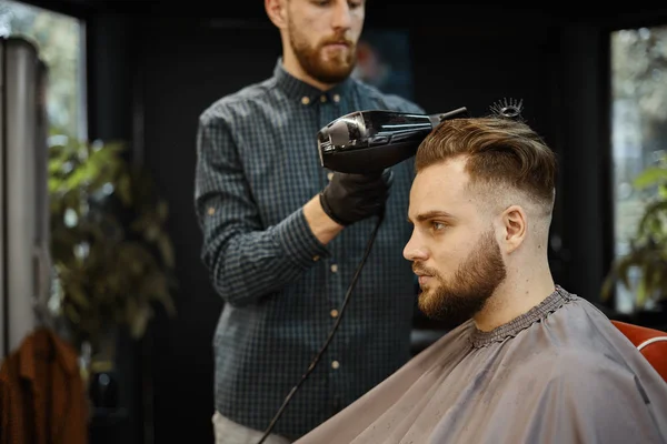 A guy doing a haircut and styling a beard — Stock Photo, Image