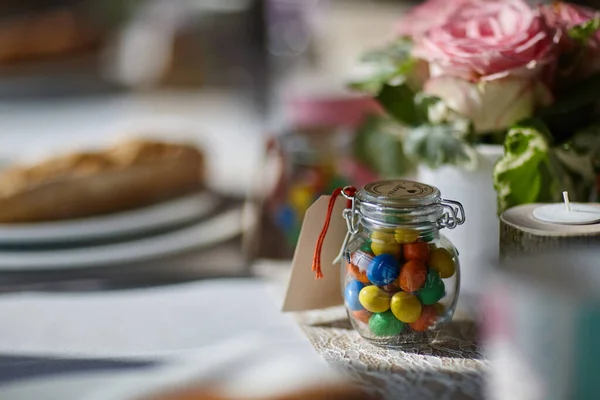 Bonbons de différentes couleurs dans un bocal en verre sur une table de mariage — Photo