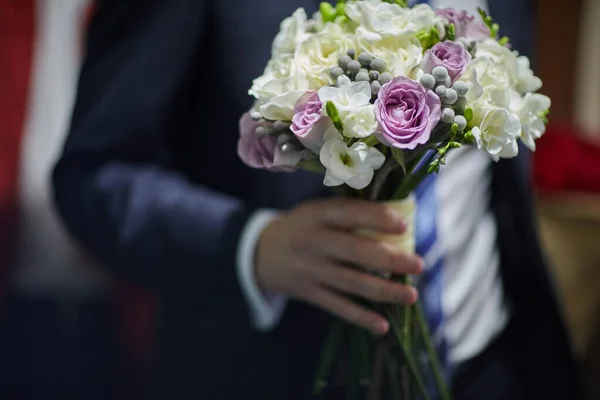 The groom holds in his hands a beautiful bouquet of the bride — Stock Photo, Image