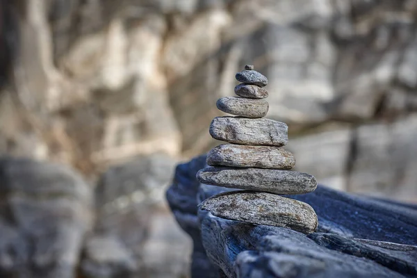 Pyramida z různých kamenů na pozadí skály — Stock fotografie