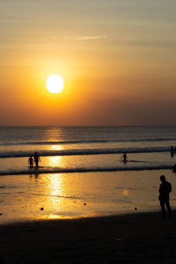 Gün batımında Bali Kuta plaj, İnsanlar oynuyor ve zevk